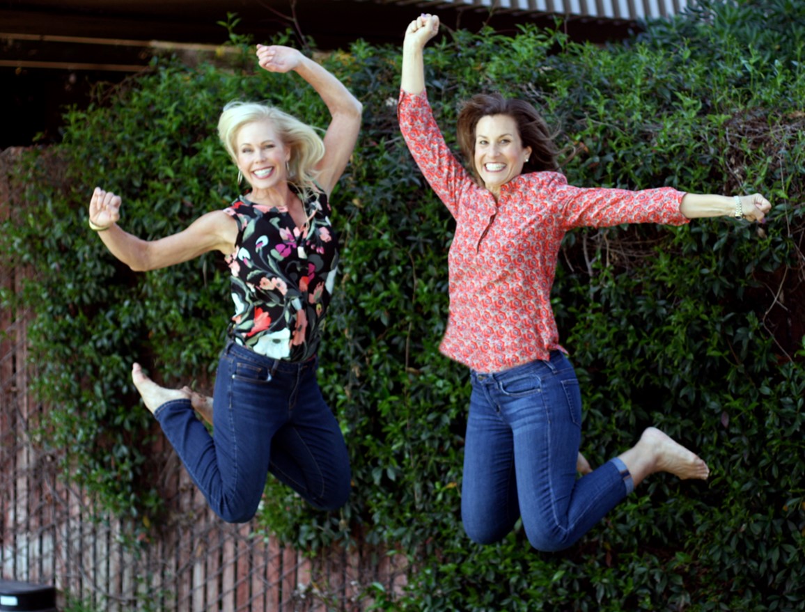 Two women jumping in the air with their hands raised.